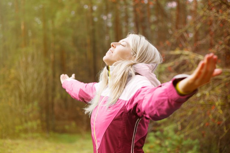 Woman with open arms wearing a pink windbreaker