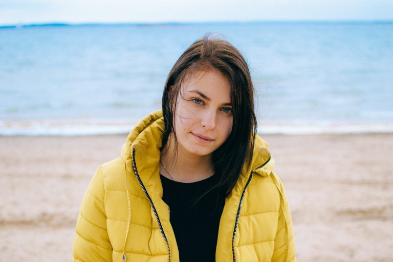 Woman wearing a yellow puffer jacket on the beach